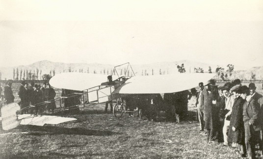 Mamet al comadament del Blériot XI mentre un grup de curiosos el contempla.